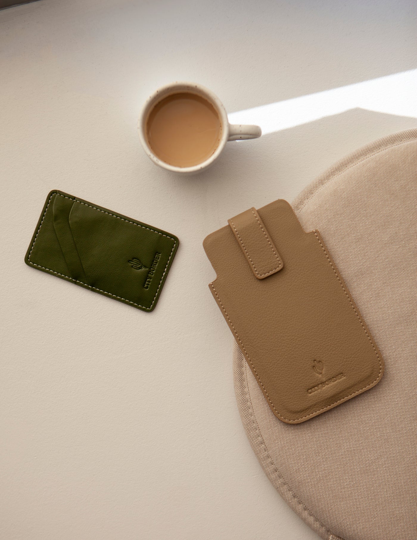 Eine grüne und eine beige Bastei Handyhülle von City Border neben einer Tasse Kaffee, lässig und stylish. Handyhülle Universal.