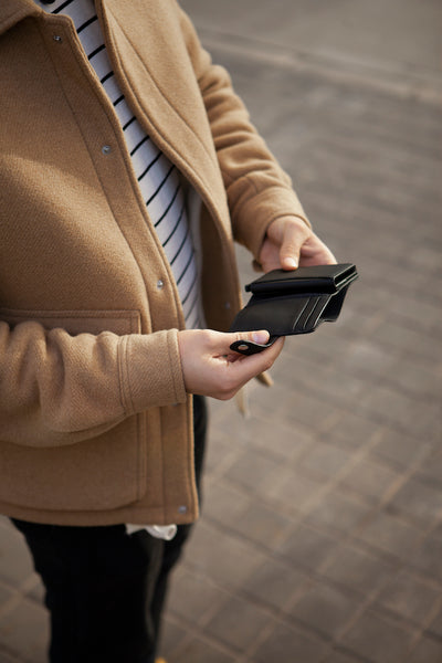 Eine Person hält den schwarzen Cardholder mit Scheinfach Kaktusleder von City Border in der Hand, während sie draußen steht.