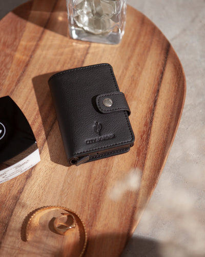 Der schwarze Cardholder mit Scheinfach Kaktusleder von City Border liegt auf einer Holzoberfläche und zeigt sein elegantes Design.